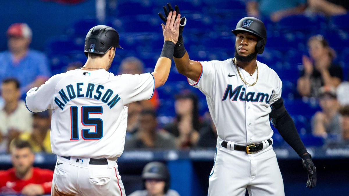Miami Marlins base runner Brian Anderson (15) reacts to scoring with teammate Bryan De La Cruz (14) during the third inning of a baseball game against the Philadelphia Phillies at LoanDepot Park on Sunday, April 17, 2022 in Miami, Florida.