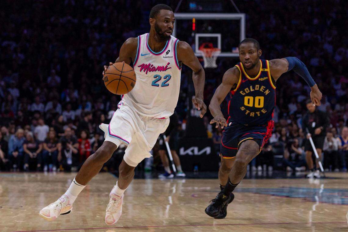 Miami Heat forward Andrew Wiggins (22) dribbles past Golden State Warriors forward Jonathan Kuminga (00) during the second half of an NBA game at Kaseya Center on March 25, 2025, in Miami.