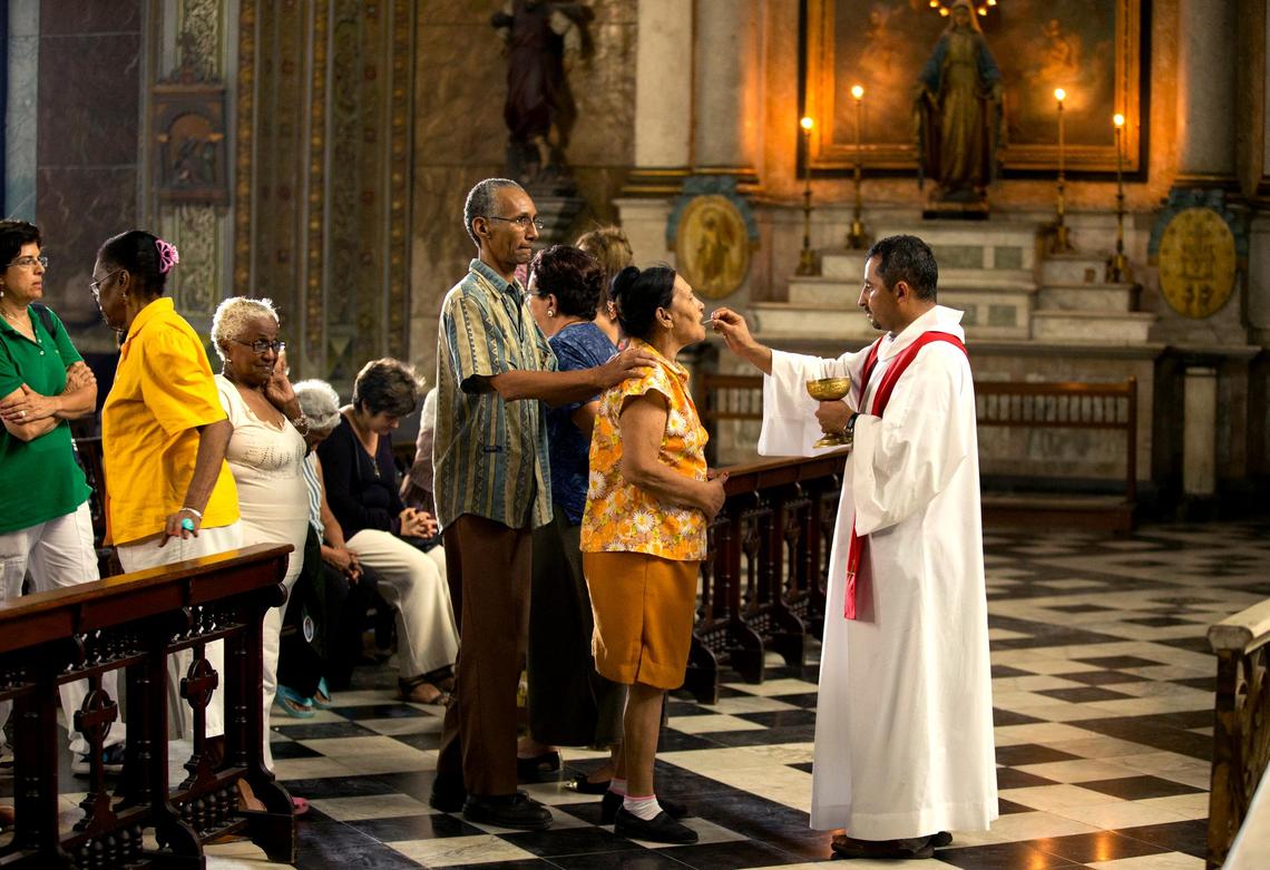 Irma Pérez receives communion by the Rev. Hector Farfan at la Merced church in Havana, Cuba.