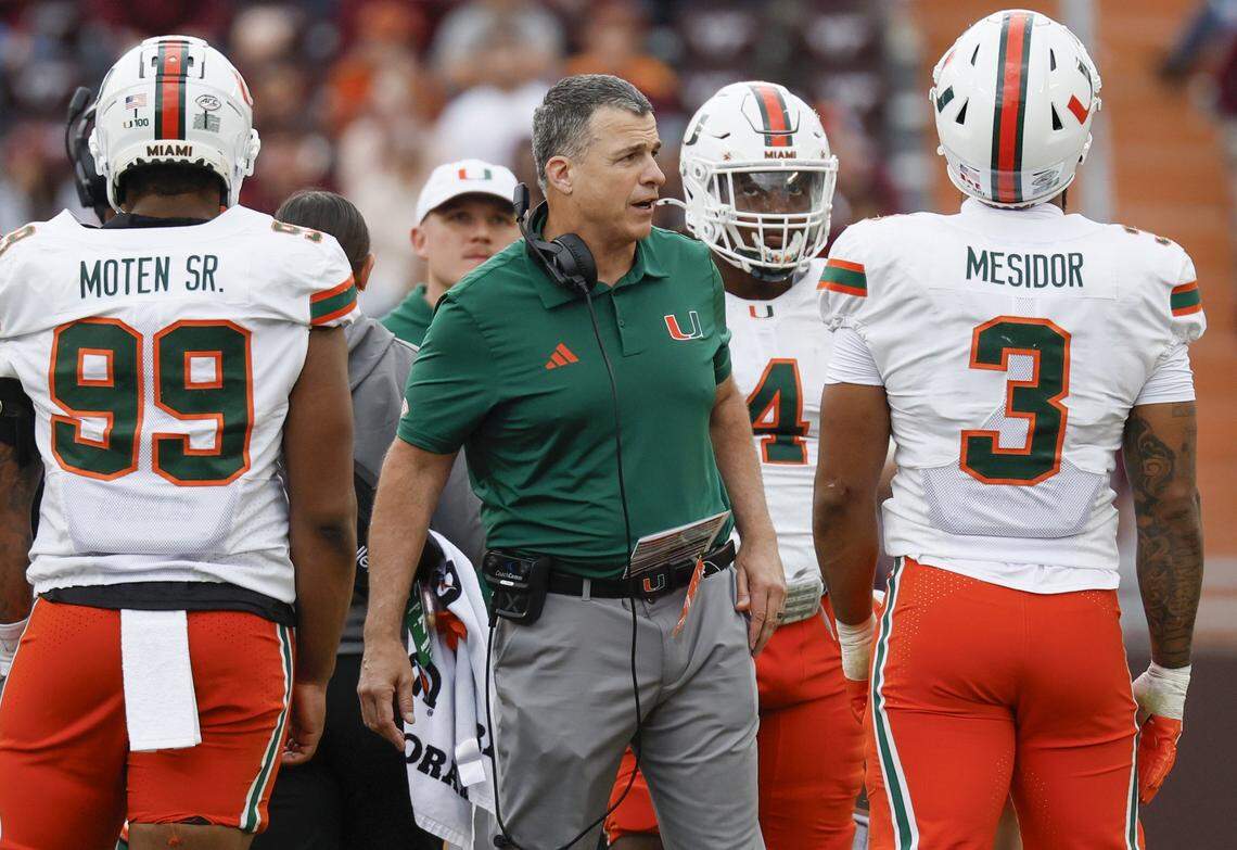 Miami Hurricanes head coach Mario Cristobal talks with players during a timeout in the second half against the Virginia Tech Hokies at Lane Stadium in Blacksburg, Virginia, on Saturday, November 22, 2025.