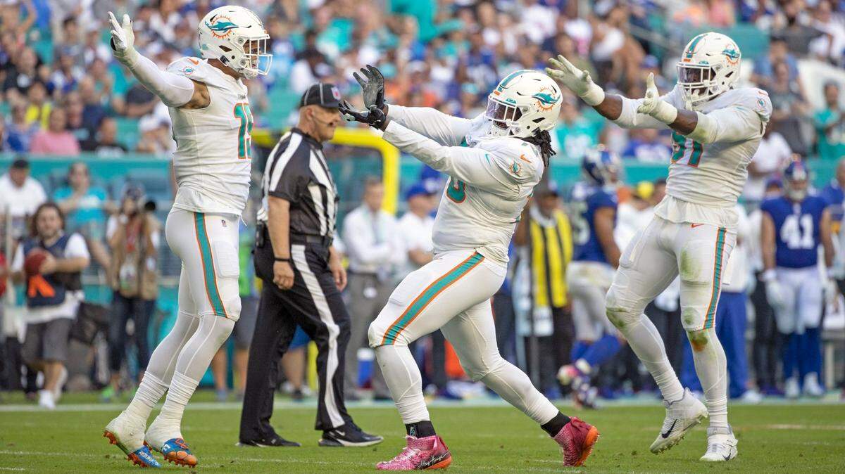 Miami Dolphins outside linebacker Jaelan Phillips (15), nose tackle Adam Butler (70) and defensive end Emmanuel Ogbah (91) react after Butler sacks New York Giants quarterback Mike Glennon (2) in the fourth quarter at Hard Rock Stadium in Miami Gardens on Sunday, December 05, 2021. ( Al Diaz Photo / Miami Herald )