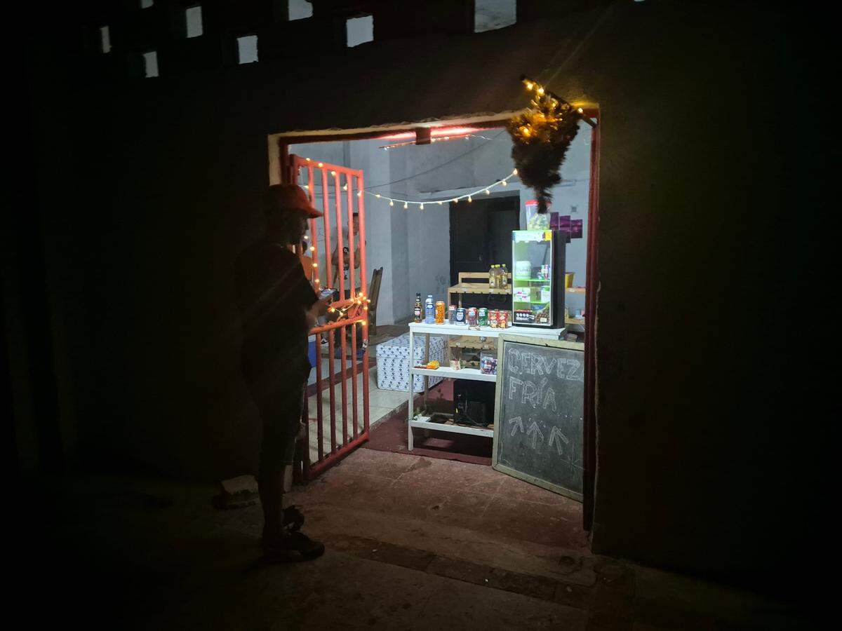 During an island-wide power outagei n Cuba, a man stands in front of a store that has electricity and advertises cold beer. Photo: Nick Kaiser/dpa/Sipa USA
