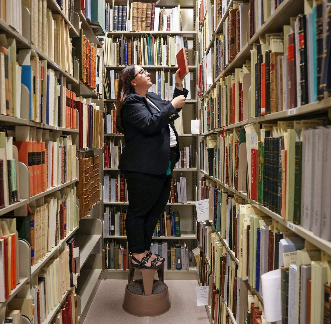 Amanda Moreno, director of the Cuban Heritage Collection, pulls a book from its vintage collection bookshelf at the University of Miami Cuba Heritage Collection in Coral Gables, Florida, on Tuesday, July 23, 2024.