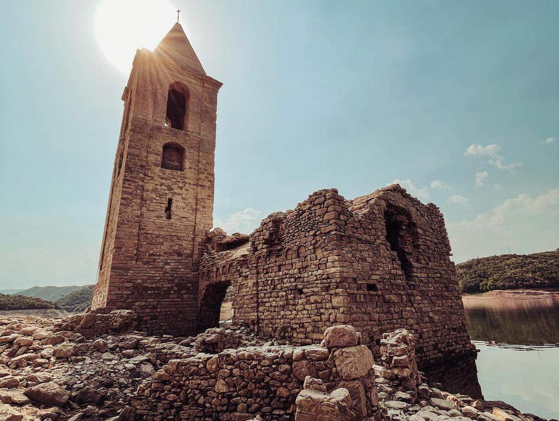 The Church of Sant Romà seen up close, rising from the dry ground of the surrounding reservoir.