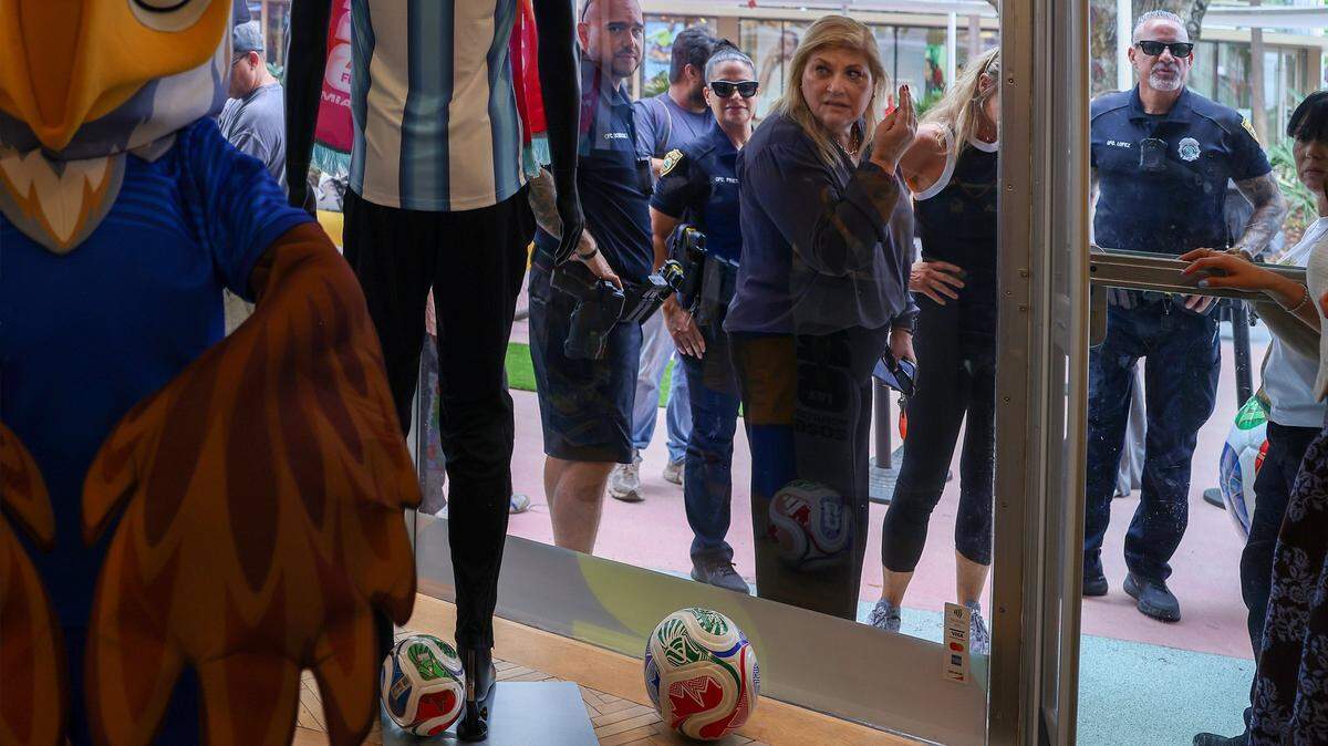 As attendees await the official ribbon-cutting, a guest peers into the FIFA World Cup store on Lincoln Road Mall, where mascots greet influencers and creators from Miami and around the world during a private shopping experience at the grand opening, Thursday, in Miami Beach, Florida.