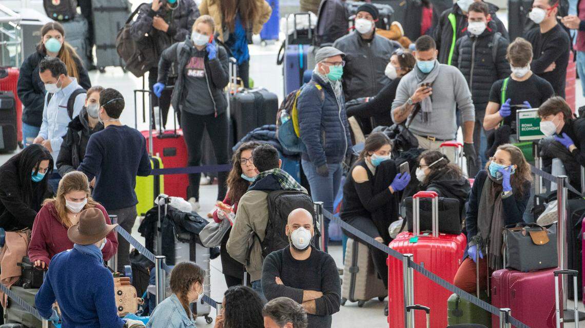 Passengers wear face masks to fend off coronavirus as they wait in line to check in for their flights, Tuesday, March 24, 2020, at JFK airport in New York.