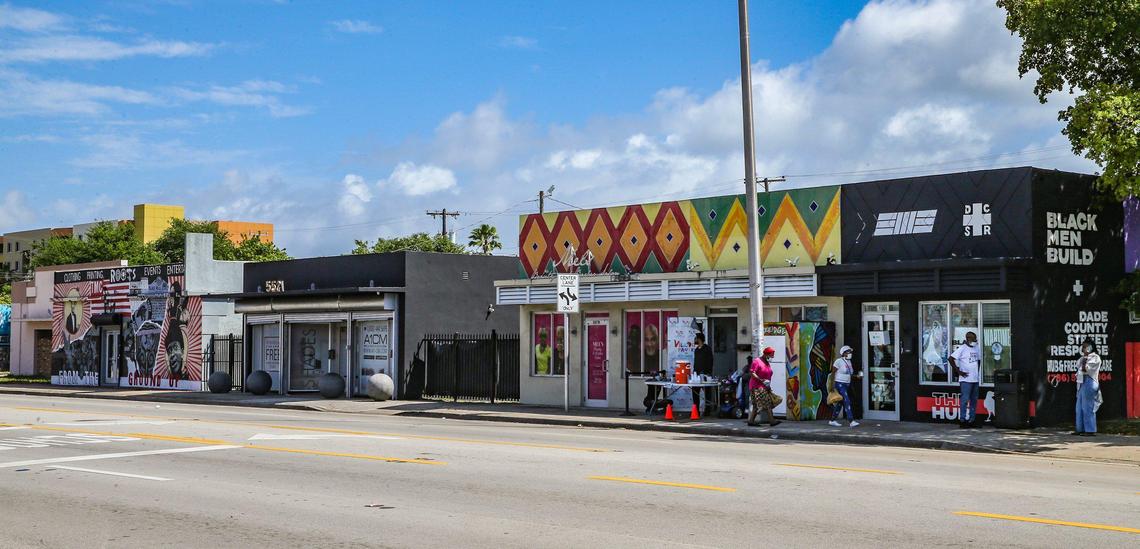 The Roots Collective Black House, far left, sits two doors down from the Village Free(dge), second from right, and the Black Men Build hub, far right, on the 5400 block of 7th Avenue in Miami, Florida, on Wednesday, March 16, 2022. Once a commercial corridor, 7th Avenue has transformed into a hub of activism.