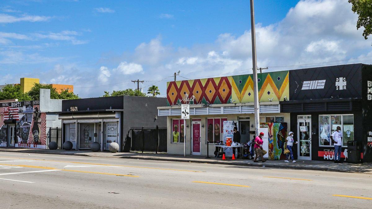 The Roots Collective Black House (far left) sits two doors down from the Village Free(dge) (second to right) and the Black Men Build hub far right) on the 5400 block of 7th Avenue in Miami, Florida on Wednesday, March 16, 2022. Once a commercial corridor, 7th Avenue has transformed into a hub of activism.