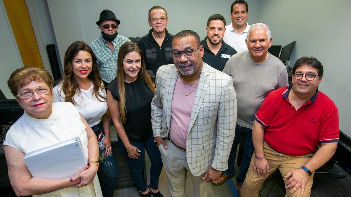 Al Santiago, center, vice president of KMTG Property Management and Investments LLC, at his office in Doral on April 16, 2021. He is accompanied by a group of his current clients who all say he has been working with them and have no complaints about him.
