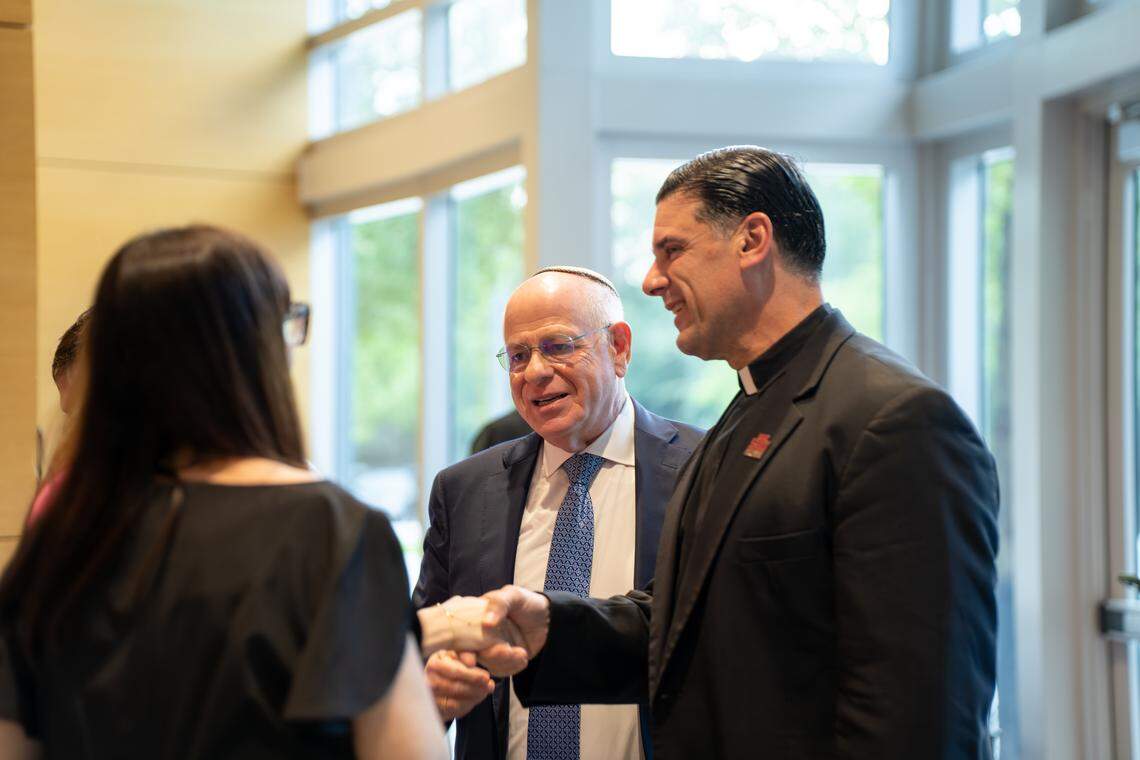 Rabbi Mario Rojzman (left) and Father Rafael Capó shake hands with attendees of an event at St. Thomas University that honored the legacy of Catholic–Jewish relations in America.