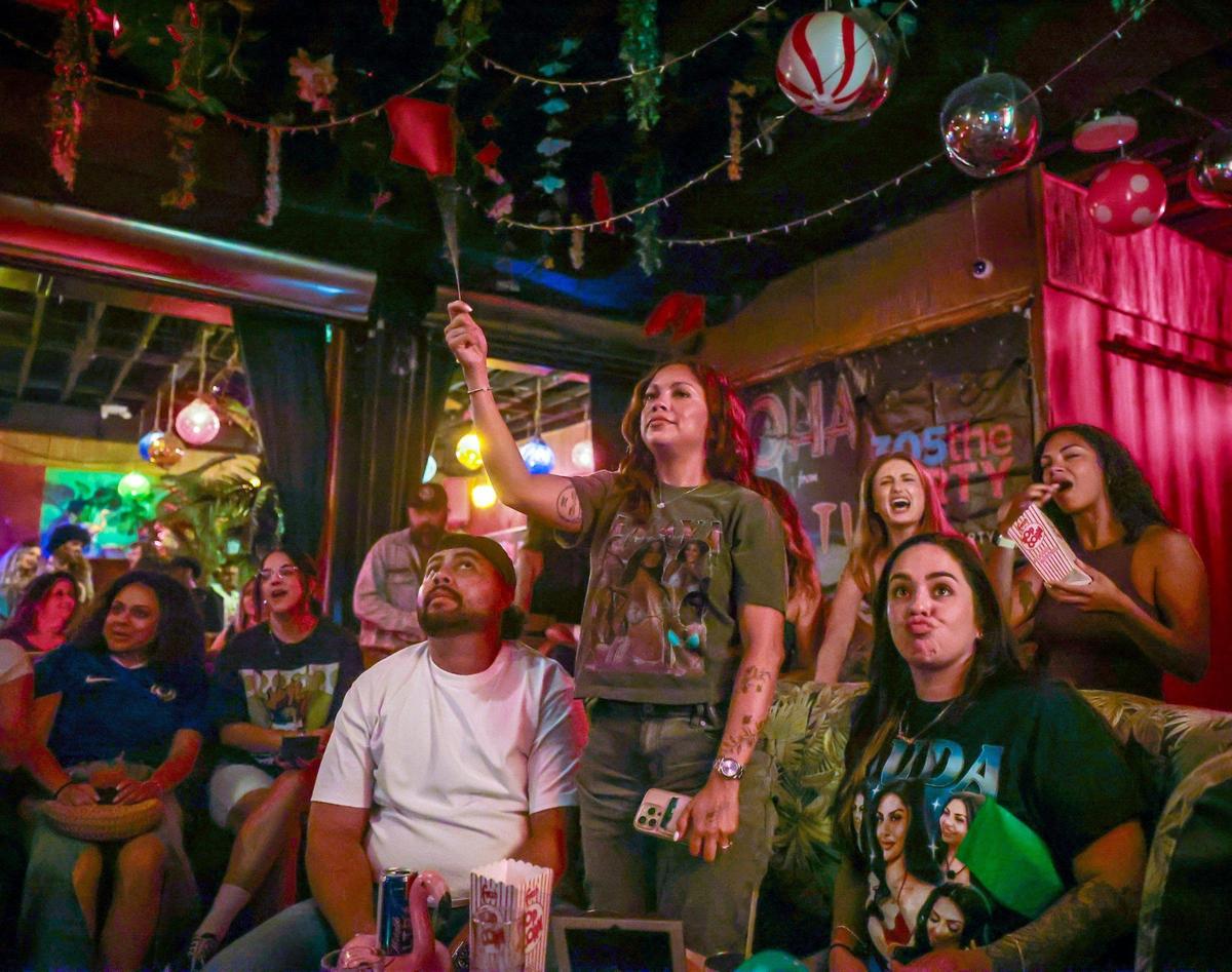Carla Lumbi, 31, center, stands to show her disapproval as she gave a contestant a red flag while attending the Love Island watch party with her friend Kareena Baga, 32, right, on Sunday, July 13, 2025, in Miami, Florida. The Dead Flamingo hosted a watch party of the popular show Love Island which featured South Florida contestants including the finalist Nicolas “Nic” Vansteenberghe, a FAU student.