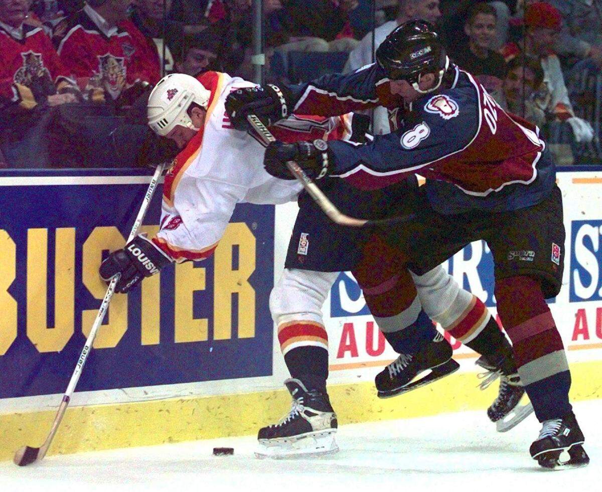 In 1997, Panthers’ left wing Mike Hough takes a hit from future Panther Sandis Ozolinsh during a loss to the Colorado Avalanche at Miami Arena. Note the Blockbuster Video advertisement. Both the team and video chain were owned by H. Wayne Huizenga.