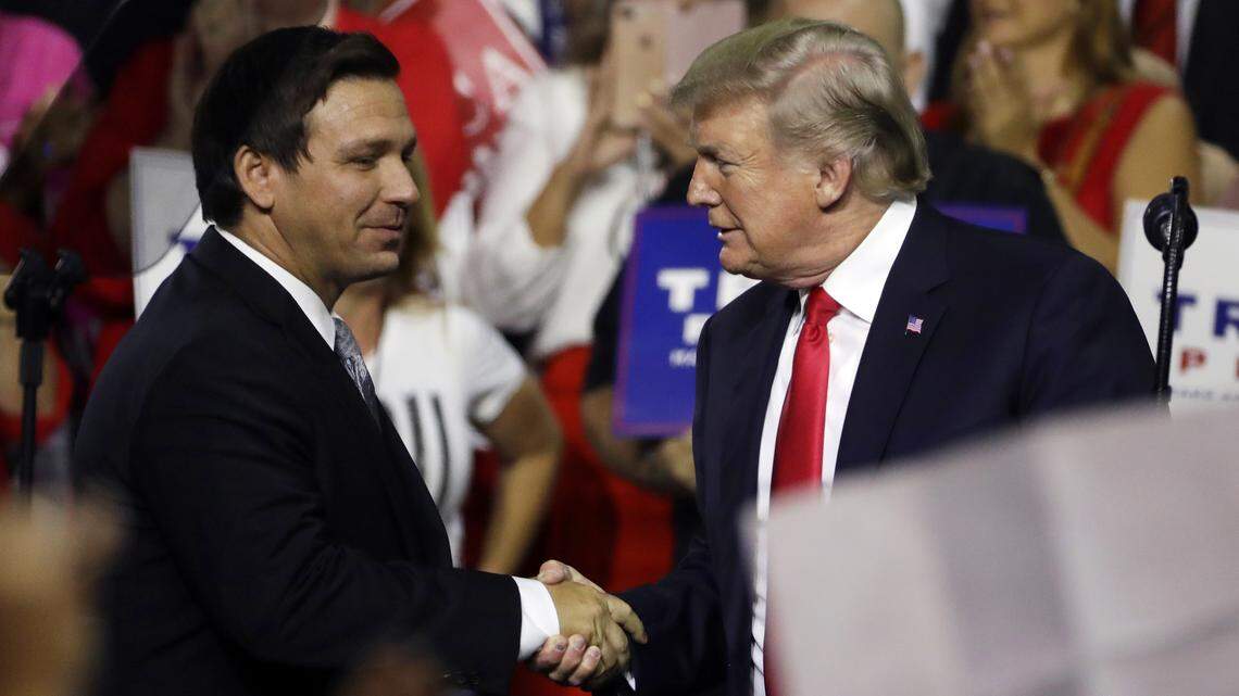 President Donald Trump, right, shakes hands with then-candidate Ron DeSantis during a rally in Tampa, July 31, 2018.