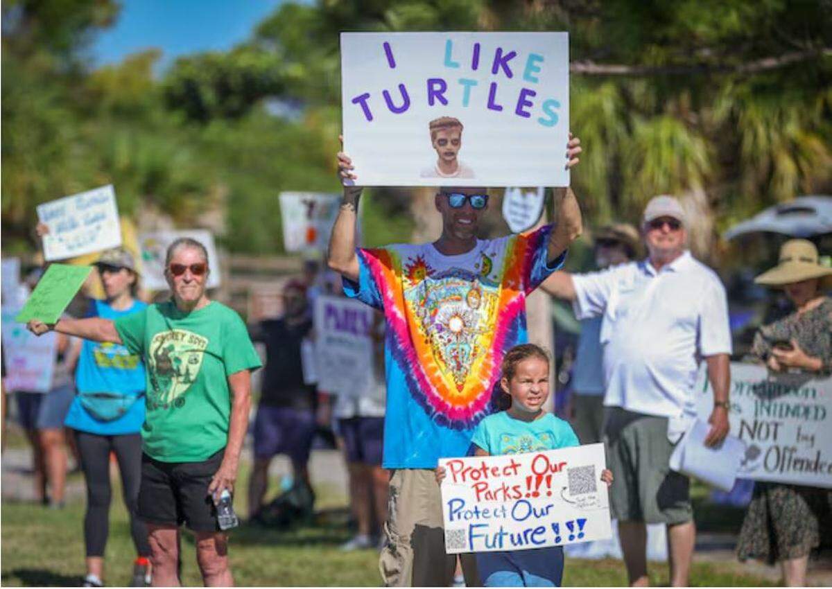 Patrick Taylor, 44, and his daughter Sophie Taylor, 6, of Dunedin, hold signs during a rally near the entrance to Honeymoon Island State Park.