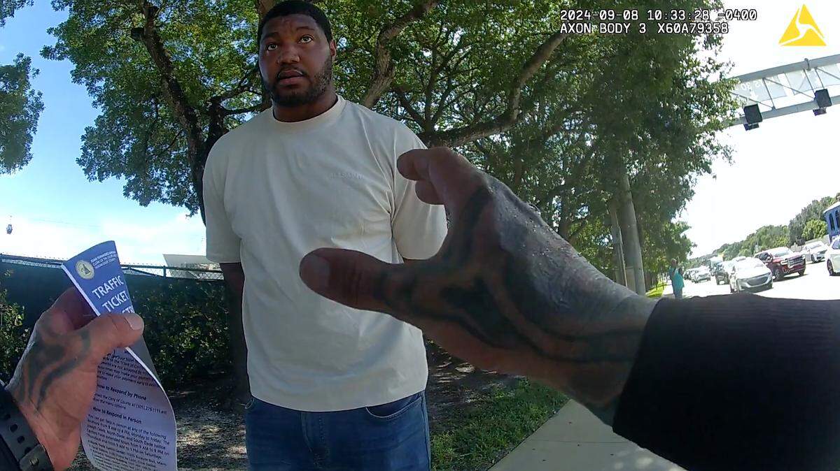 Miami-Dade Police officer Danny Torres handcuffs Miami Dolphins defensive tackle Calais Campbell who had stopped to help his teammate Tyreek Hill. Miami-Dade Police detained Hill for speeding by Hard Rock Stadium, Sunday, Sept. 8, 2024, hours before the Dolphins played their season opener against the Jacksonville Jaguars.