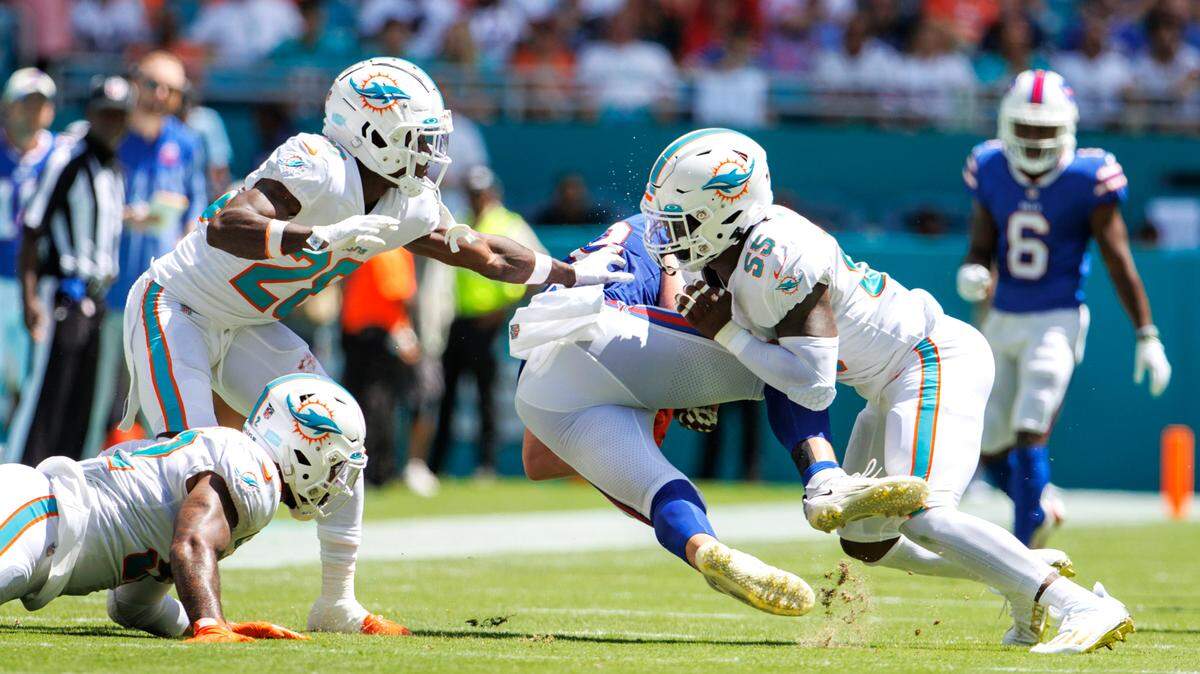 El cornerback de los Dolphins, Kader Kohou (28) y los linebackers Elandon Roberts (52) y Jerome Baker (55) atacan al tight end de los Buffalo Bills, Dawson Knox, en el primer cuarto del partido celebrado el 25 de septiembre de 2022 en el Hard Rock Stadium, en Miami Gardens, Florida.
