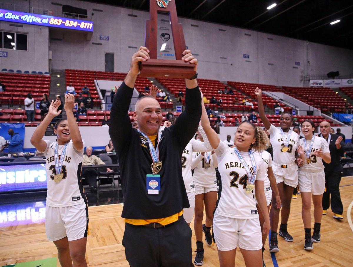 American Heritage head coach Greg Farias holds the state championship trophy after defeating Bishop Moore in the Class 5A girls basketball state championship at the RP Funding Center in Lakeland on Saturday, February 26, 2022. It’s the schools fifth state championship in a row.