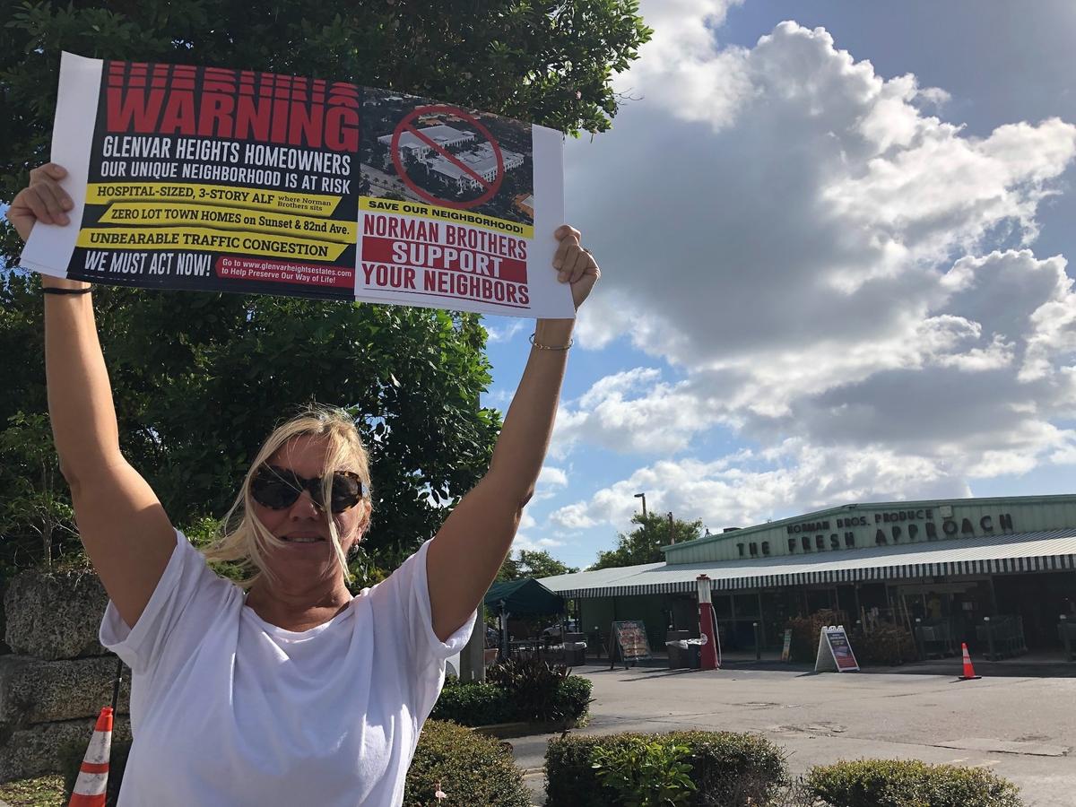 Mary Faraldo holds a sign while protesting the planned development of the Norman Brothers Produce market into an assisted-living facility and office park. Roughly 20 people joined Faraldo for the protest on May 17, 2021.