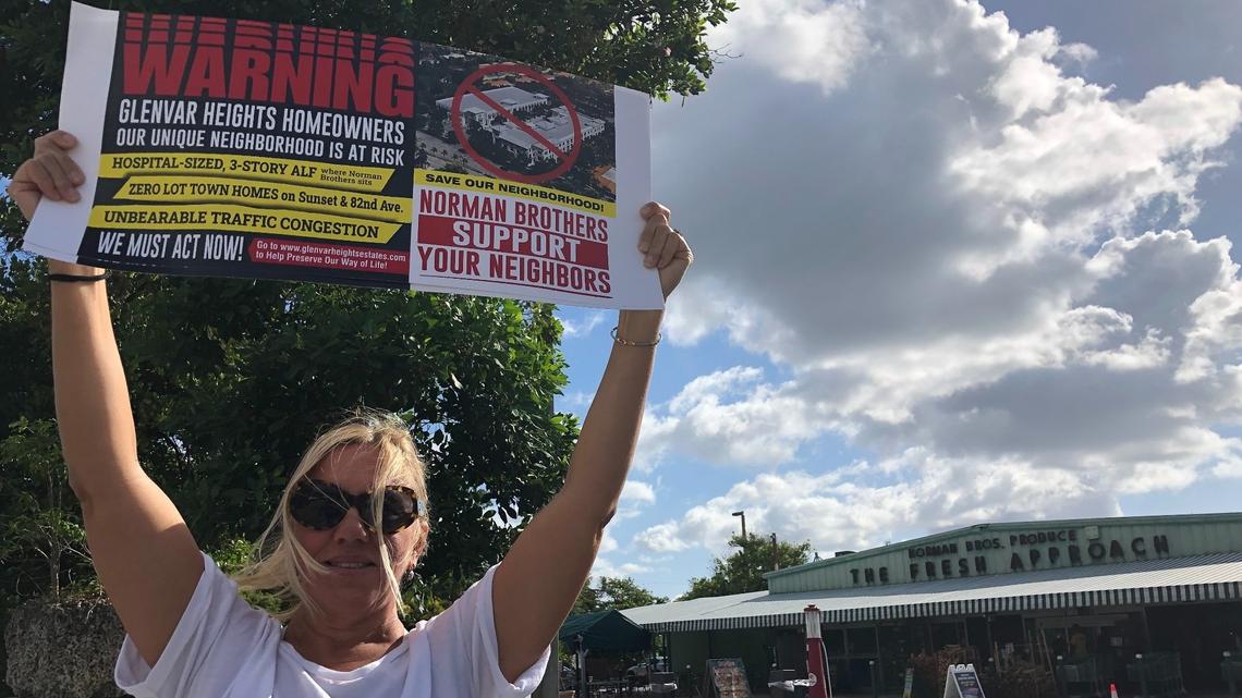 Mary Faraldo holds a sign while protesting the planned development of the Norman Brothers Produce market into an assisted-living facility and office park. Roughly 20 people joined Faraldo for the May 17, 2021 protest.