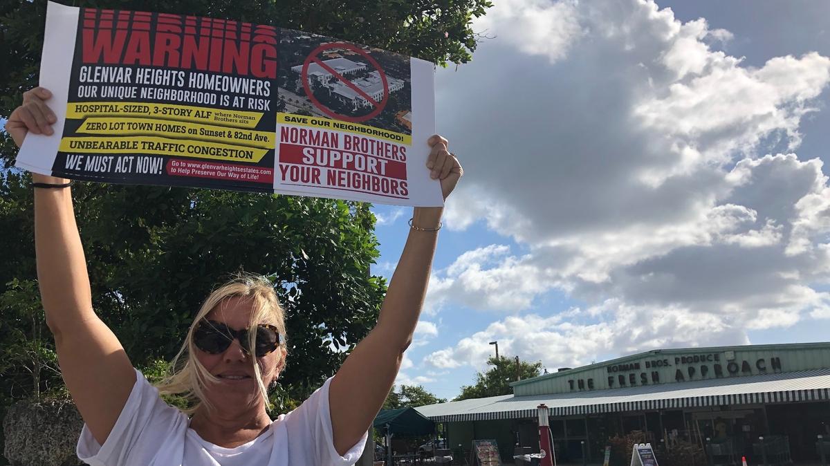 Mary Faraldo holds a sign while protesting the planned development of the Norman Brothers Produce market into an assisted-living facility and office park. Roughly 20 people joined Faraldo for the May 17, 2021 protest.