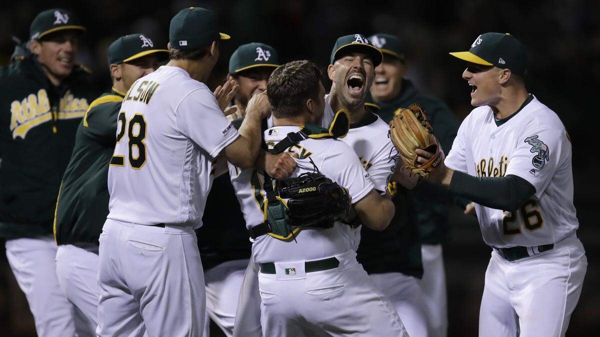 Oakland Athletics’ Mike Fiers, center, celebrates with Matt Olson (28) Chad Pinder (18) and Matt Chapman (26) after pitching a no hitter against the Cincinnati Reds at the end of a baseball game Tuesday, May 7, 2019, in Oakland, Calif. (AP Photo/Ben Margot)