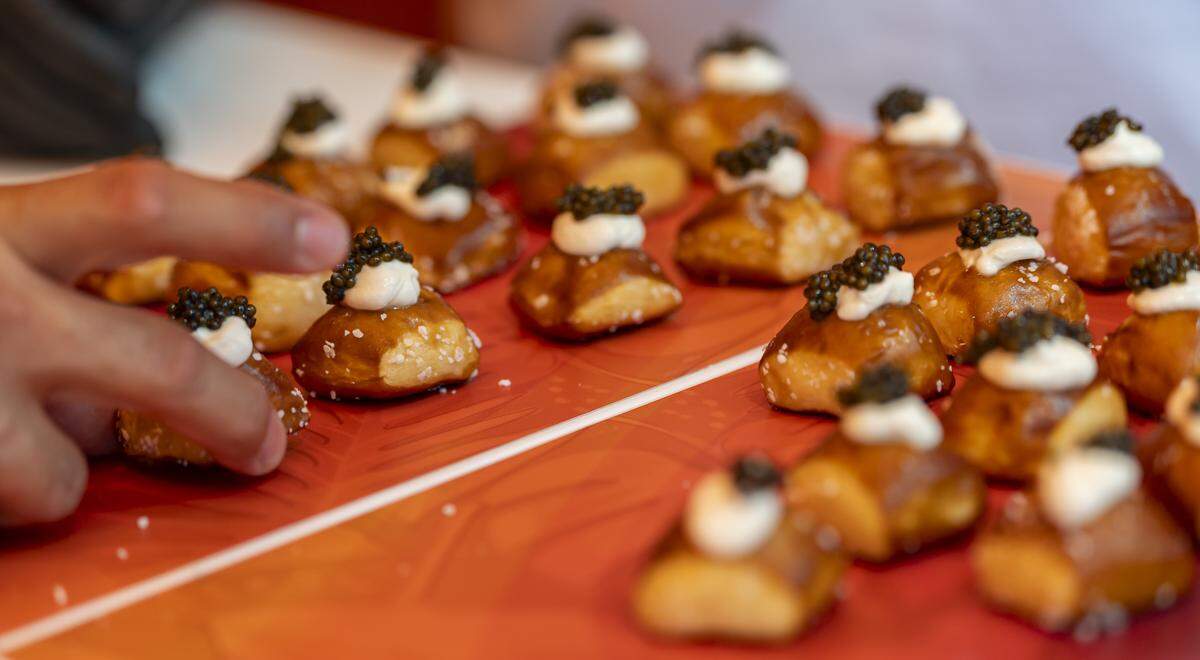 A King's Hawaiian Bites booth invite guests to try a pretzel bite topped with Crème fraîche and caviar at the Goya Foods' Grand Tasting Village during the Food Network South Beach Wine & Food Festival on Saturday, Feb. 21, 2026, in Miami Beach, Fla.