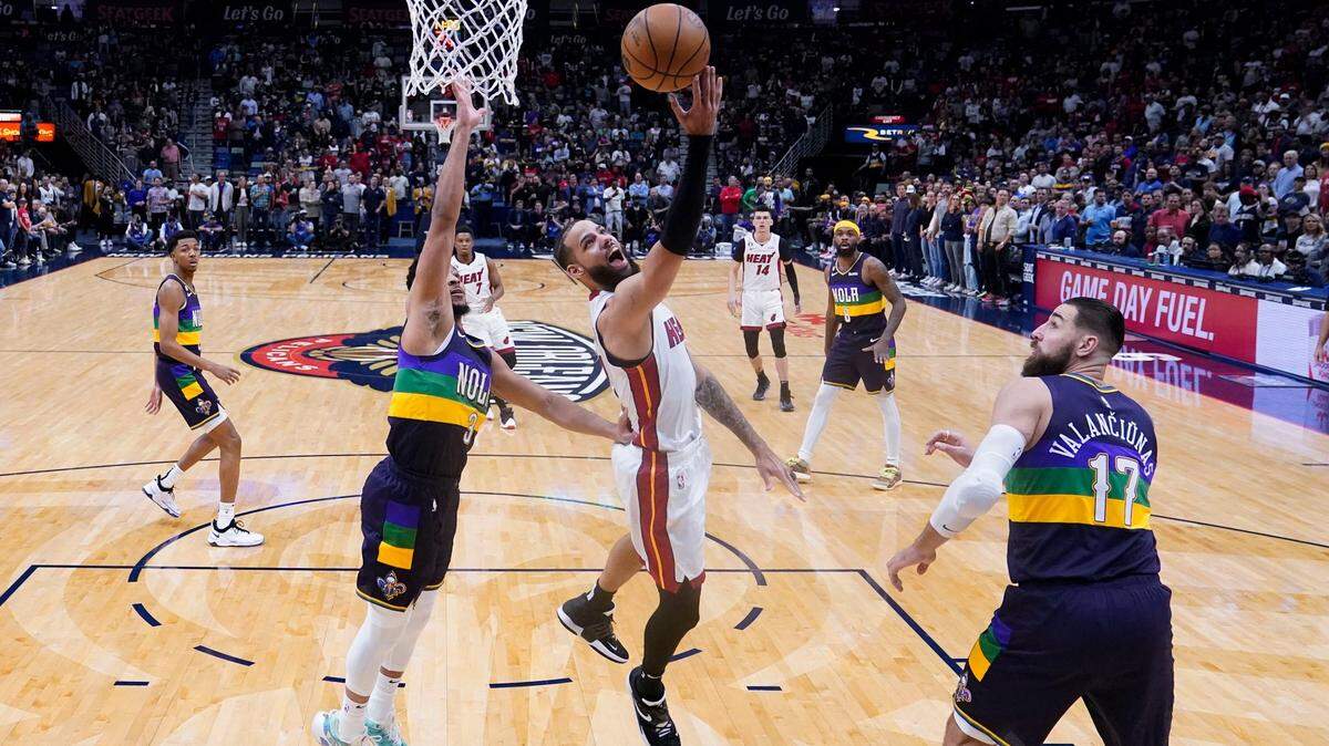 Miami Heat forward Caleb Martin (16) goes to the basket between New Orleans Pelicans guard CJ McCollum (3) and center Jonas Valanciunas (17) in the first half of an NBA basketball game in New Orleans, Wednesday, Jan. 18, 2023.