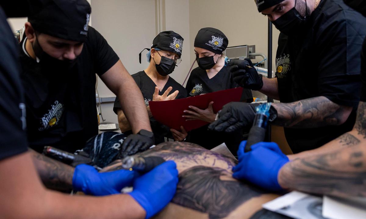 Dr. Steven Burns, 60, and R.N. Sofia Reichard Manrique, 25, center, monitor Dom Groenveld, who is anesthetized, as Sedation Ink artists work on a back tattoo at a surgical office on Monday, Jan. 20, 2025, in Miami, Fla. Sedation Ink offers tattooing under anesthesia, allowing clients to complete extensive body art in a single session.