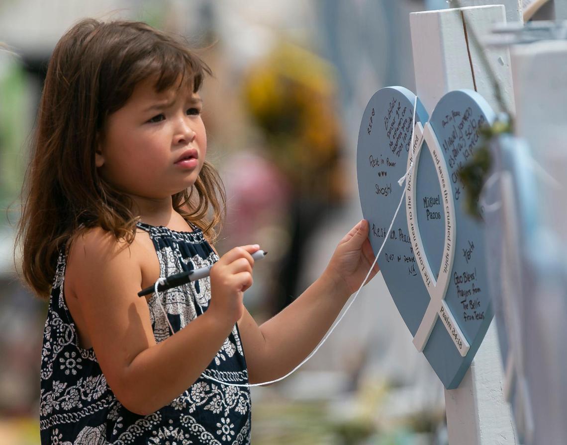 Shoshanna Pagel, 5, writes a message on a makeshift marker at the Surfside Wall of Hope & Memorial as rescue teams continue their recovery mission at the collapsed Champlain Towers South building in Surfside on Monday, July 12, 2021.