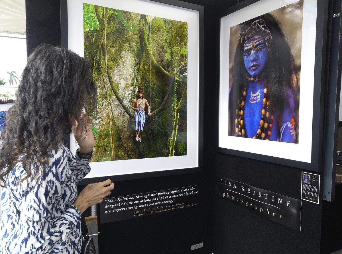 A festival attendee examines works by graphic artist Lisa Kristine during the 2018 Coconut Grove Arts Festival.
