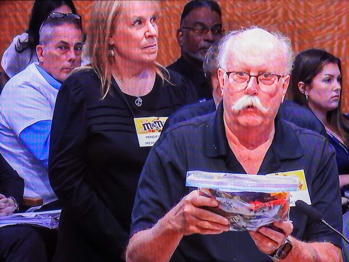 John Dolson, who described himself as “a proud M&M,” holds a bag of candy while speaking at the City of Miami Commission meeting on Thursday, Oct. 24, 2024, at City Hall in Miami. Public comments were heard on the controversial pension plan first co-sponsored by Commissioners Miguel Angel Gabela and Christine King. Public comments were heard on the controversial pension plan first co-sponsored by Commissioners Miguel Angel Gabela and Christine King and later revoked his support after public outcry.