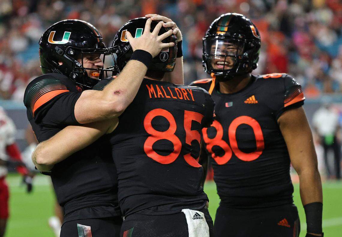 Miami Hurricanes tight end Will Mallory (85) is congratulated by quarterback Tyler Van Dyke (9) and tight end Elijah Arroyo (80) after scores a touchdown against the North Carolina State Wolfpack during the third quarter of their ACC football game at Hard Rock Stadium on Saturday, October 23, 2021 in Miami Gardens, Florida.