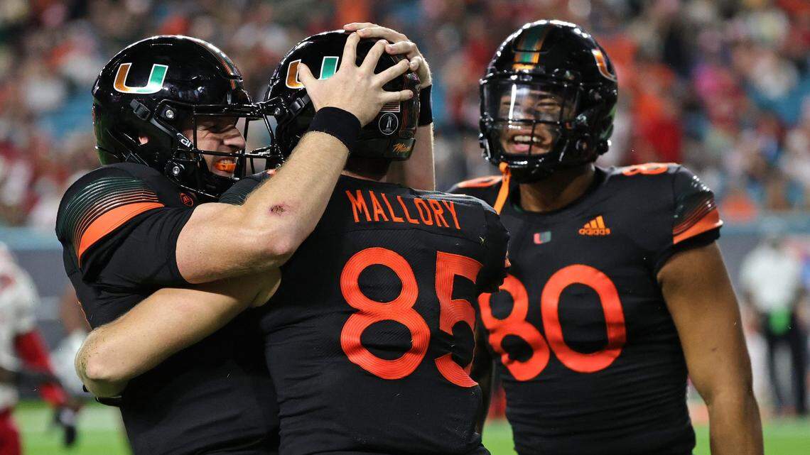 Miami Hurricanes tight end Will Mallory (85) is congratulated by quarterback Tyler Van Dyke (9) and tight end Elijah Arroyo (80) after scores a touchdown against the North Carolina State Wolfpack during the third quarter of their ACC football game at Hard Rock Stadium on Saturday, October 23, 2021 in Miami Gardens, Florida.