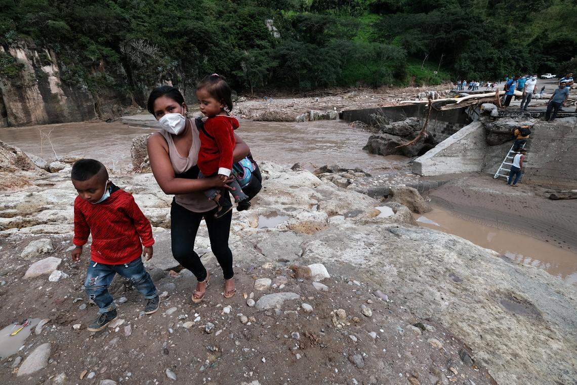 A woman with two kids manages to walk across the destroyed bridge over the Higuito river on November 19, 2020, in Copan, Honduras.