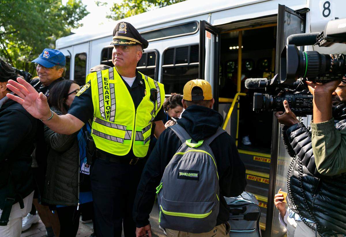 El jefe de policía de Edgartown, Bruce R. McNamee, ayuda a migrantes venezolanos a subir a un autobús en la Iglesia Episcopal de St. Andrews el viernes, 16 de septiembre de 2022, en Edgartown, Misa en la isla de Marthas Vineyard.