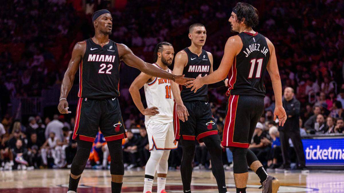 El delantero del Miami Heat, Jimmy Butler (22), felicita a su compañero de equipo Jaime Jaquez Jr. (11) en presencia de Tyler Herro (14) durante un partido de la NBA contra los New York Knicks en el Kaseya Center el 30 de octubre de 2024, en Miami.