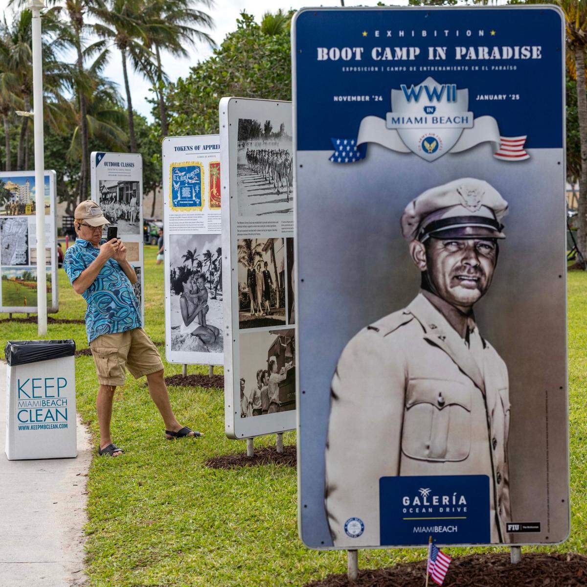 A man takes a cell phone photo of the temporary outdoor exhibition: “Boot Camp in Paradise: World War II in Miami Beach,” featuring over 150 photographs and printed materials from 1942-1945, when Miami Beach hosted over 600,000 U.S. troops training for combat, during the 16th Annual Veterans Day Parade off Ocean Drive on Monday, Nov. 11, 2024, in Miami Beach, Fla.