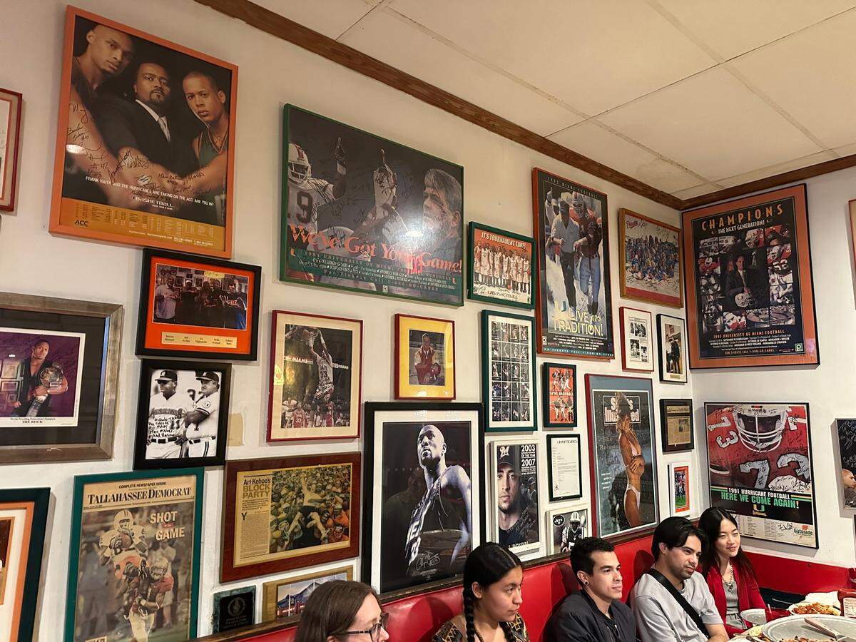 One of The Big Cheese’s Big Cheese Wall of Fame features sports memorabilia photos from Miami teams including University of Miami Hurricanes and Miami Dolphins on the evening of March 5, 2025.