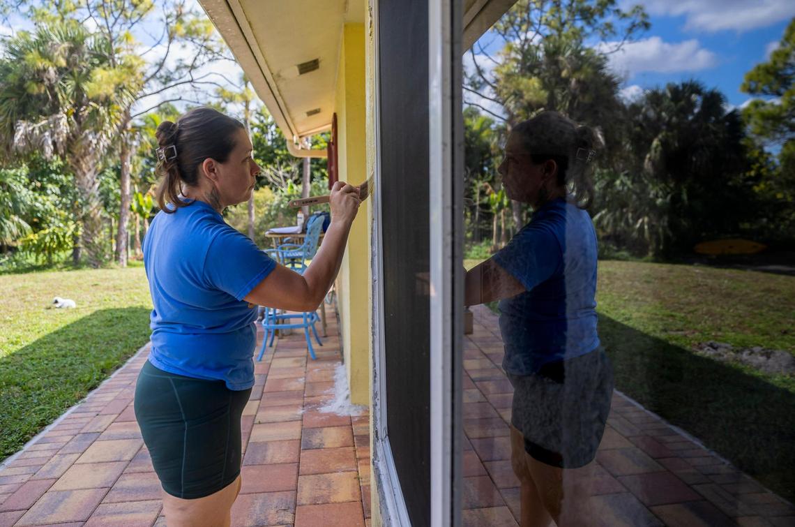 Kelly Coulter, 44, paints the trim on her newly installed impact windows on Wednesday, Jan. 31, 2023, in West Palm Beach, Fla. Coulter, and her husband, Ray, used Ygrene funding to finance a brand new roof and impact windows before Ygrene yanked the financing for everyone in Florida.