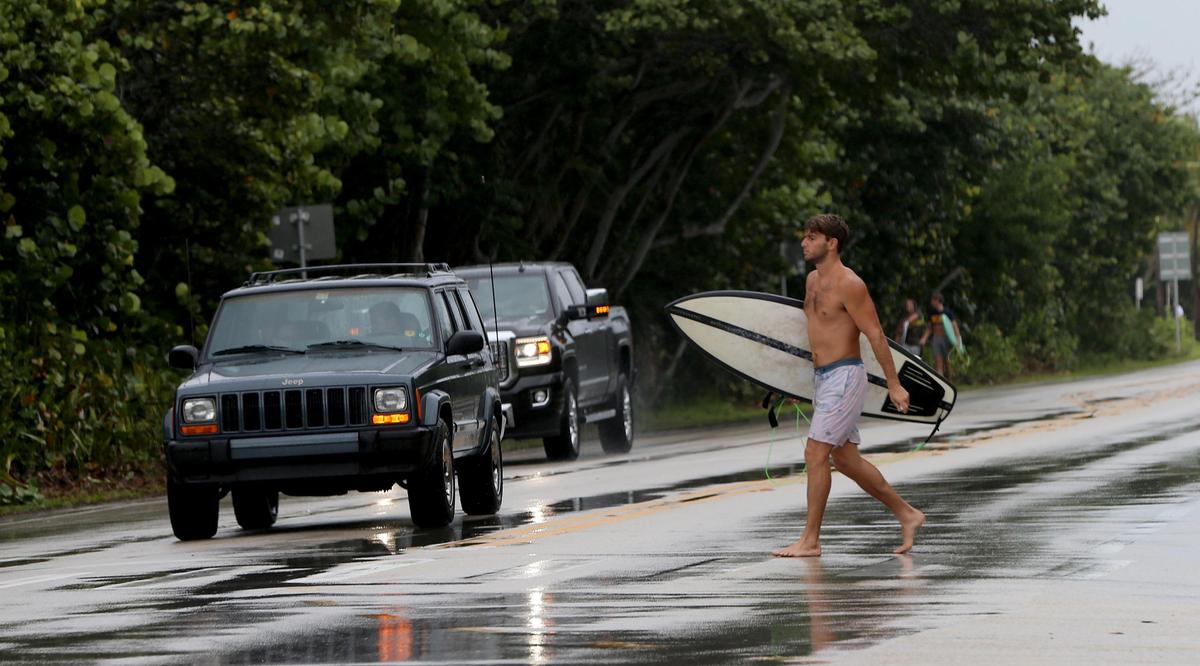 A surfer crosses A1A on his way to the Spanish River Park beach in Boca Raton as Hurricane Dorian is ‘beginning to inch northwestward’ while still pounding the Bahamas on Tuesday, Sept. 3, 2019.