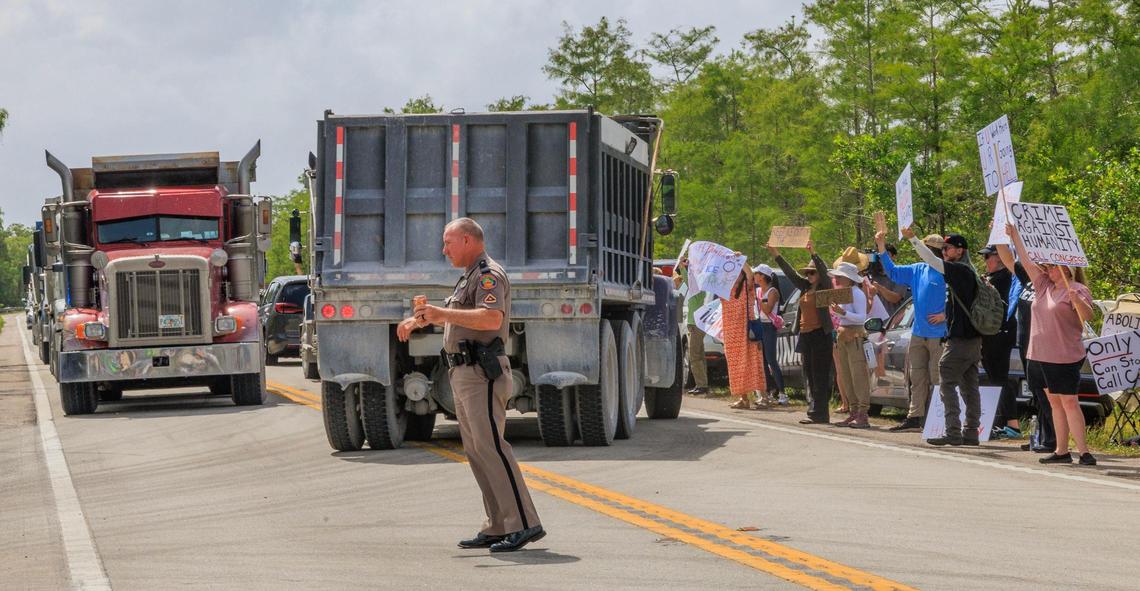 A Florida State trooper directs the traffic of trucks entering the Dade-Collier Training and Transition Airport as hundreds of protesters gathered during the “Stop Alligator Alcatraz” protest in opposition to the construction of a massive detention facility for undocumented immigrants on the site, which is in the middle of the Florida Everglades, in Ochopee, Florida, on Saturday June 28, 2025.