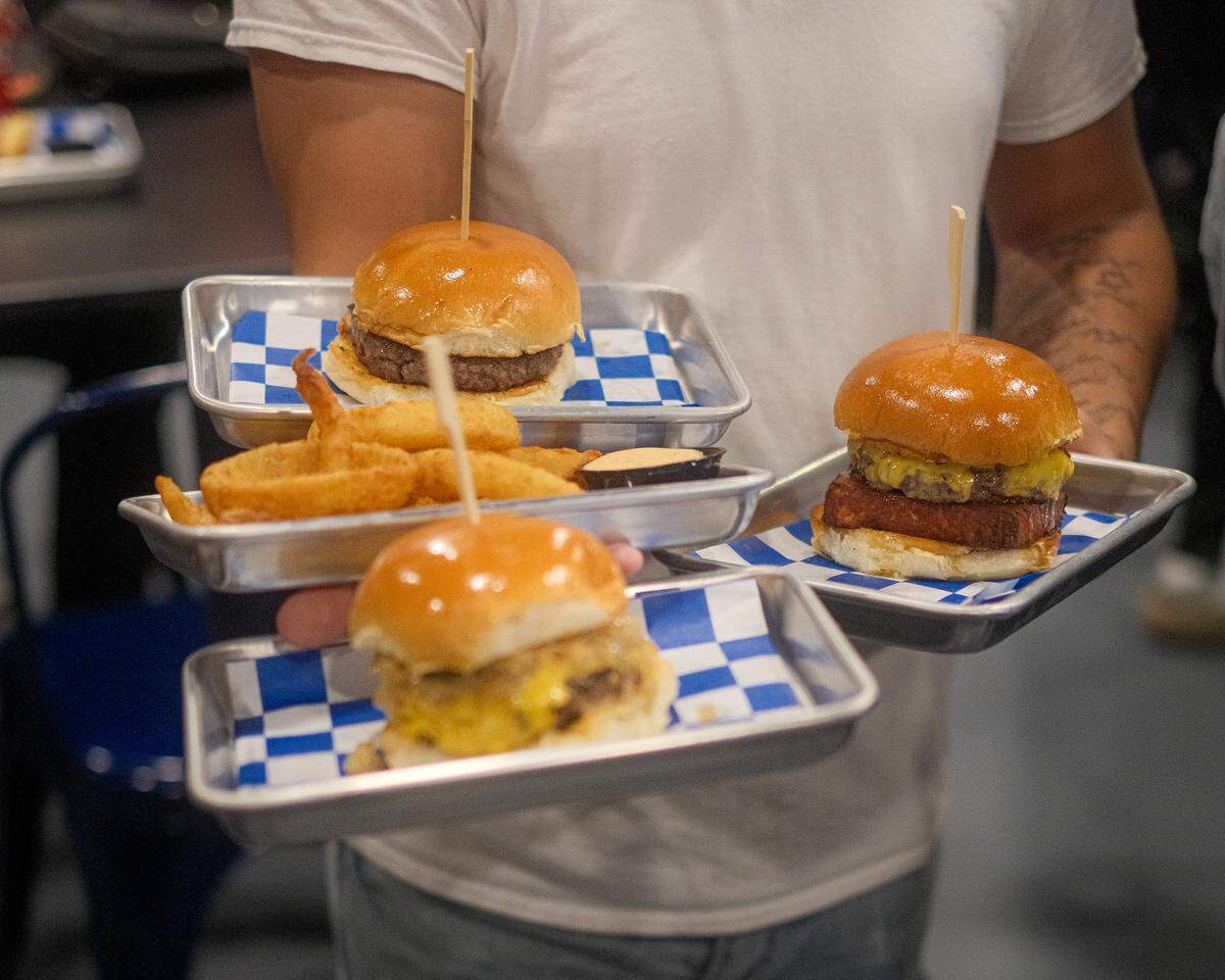 Burgers at Lala’s, including The Maxwell at right, which features chopped pepperoni, hot honey and queso frito.