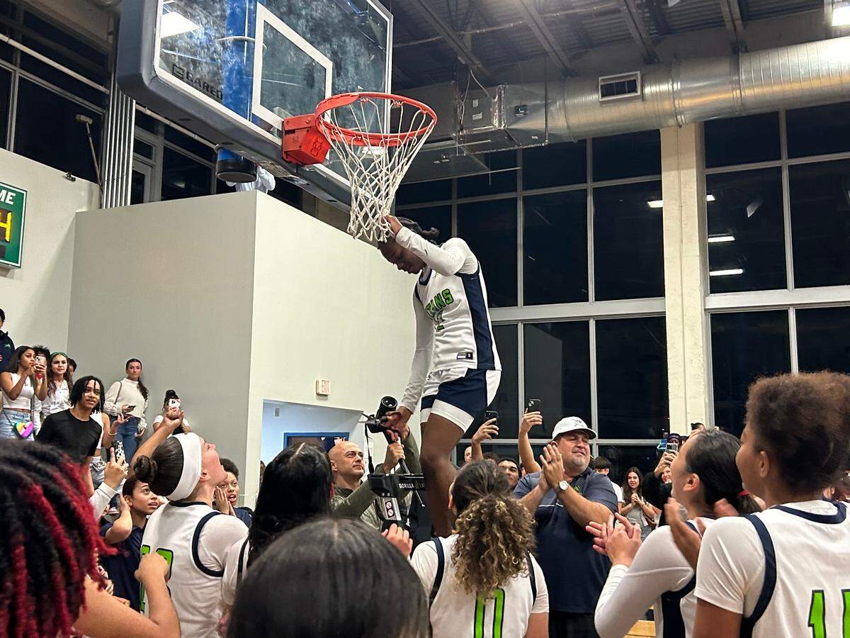 SLAM guard Jim’miyah Branton cuts down the net after she helped the Titans win the Region 4-4A girls’ basketball championship on Thursday night.