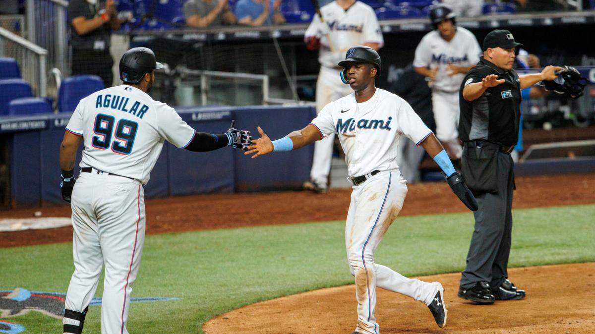 Miami Marlins right fielder Jesus Sanchez (7) is congratulated by Jesus Aguilar (99) after scoring on a sacrifice fly by Jazz Chisholm Jr. (2) during the ninth inning of a baseball game against the Washington Nationals at LoanDepot Park on Wednesday, May 18, 2022 in Miami, Florida..
