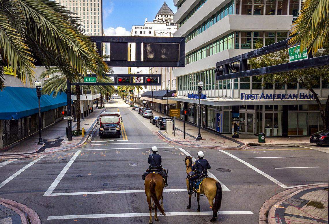 City of Miami Mounted Patrol Officers Loisel Cruz riding Ike, at left, and Ruben Gonzalez riding Cody, at right, patrol along a quiet and mostly shuttered Flagler Street in downtown Miami due to the threat of the coronavirus on Wednesday, April 1, 2020.