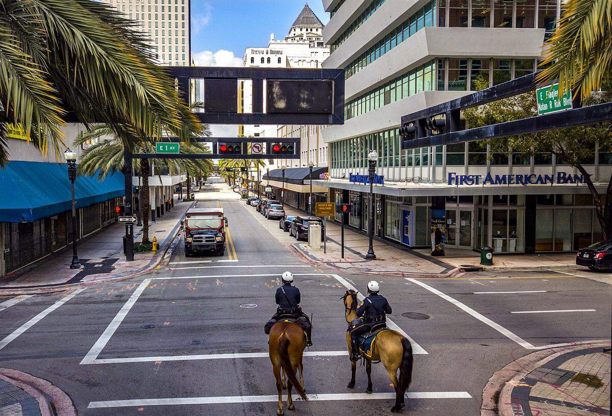 City of Miami Mounted Patrol Officers Loisel Cruz riding Ike, at left, and Ruben Gonzalez riding Cody, at right, patrol along a quiet and mostly shuttered Flagler Street in downtown Miami due to the threat of the coronavirus on Wednesday, April 1, 2020.