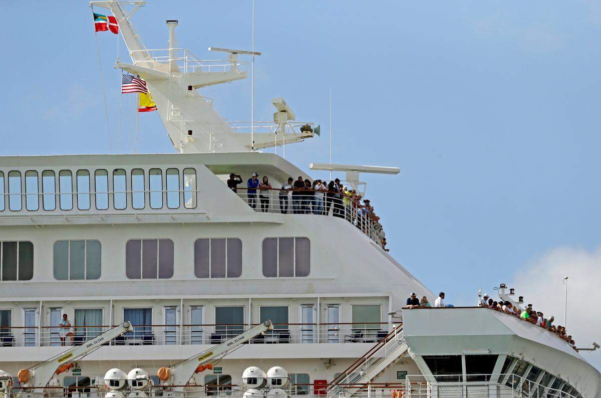 Carnival Fascination passengers look out from their balconies at PortMiami as the coronavirus pandemic continues on March 17, 2020.