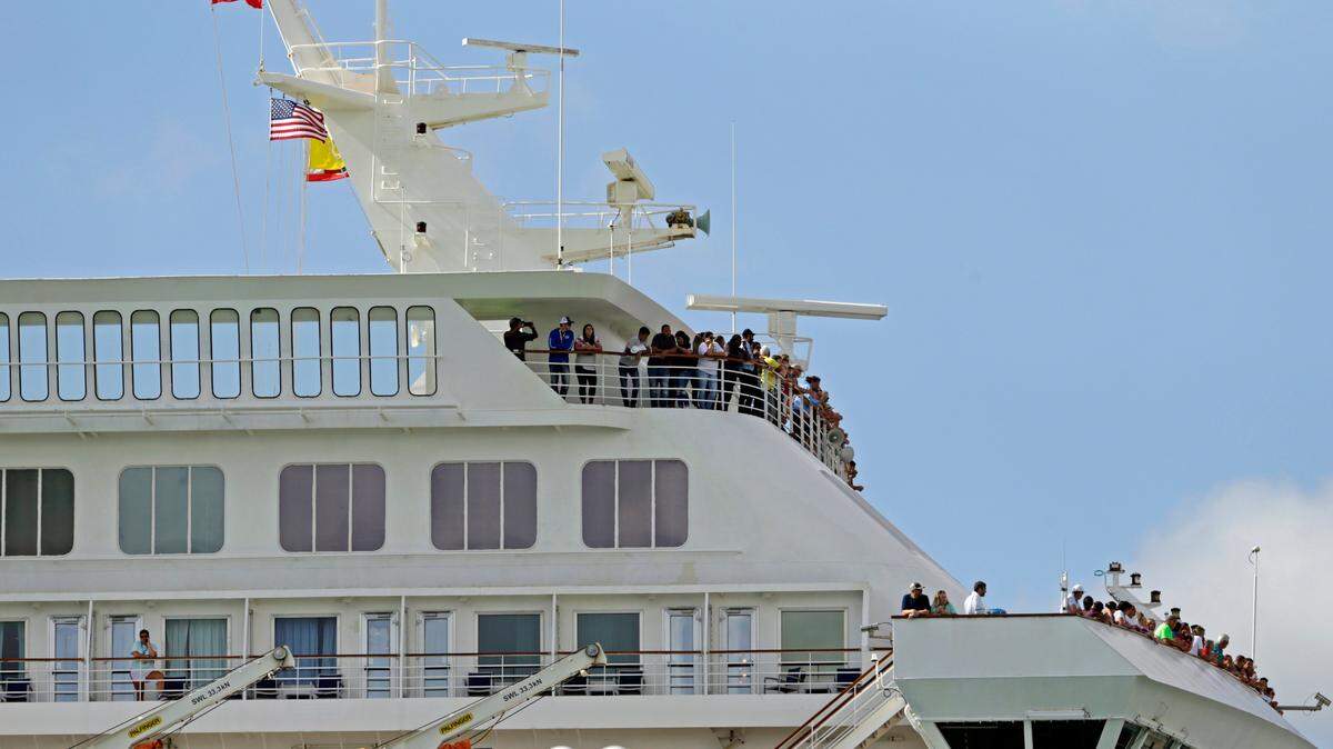 Carnival Fascination passengers look out from their balconies at PortMiami as the coronavirus pandemic continues on March 17, 2020.