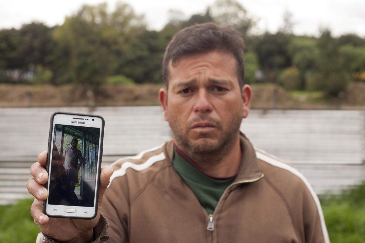 Elvis Cuevas, from Maracaibo, Venezuela, shows a picture of his father, who is ill in Venezuela. Cuevas is trying to bring him to Colombia for treatment. Cuevas and his family had been living on the streets in Bogotá, Colombia, before he recently found a job as the night watchman at a car lot.