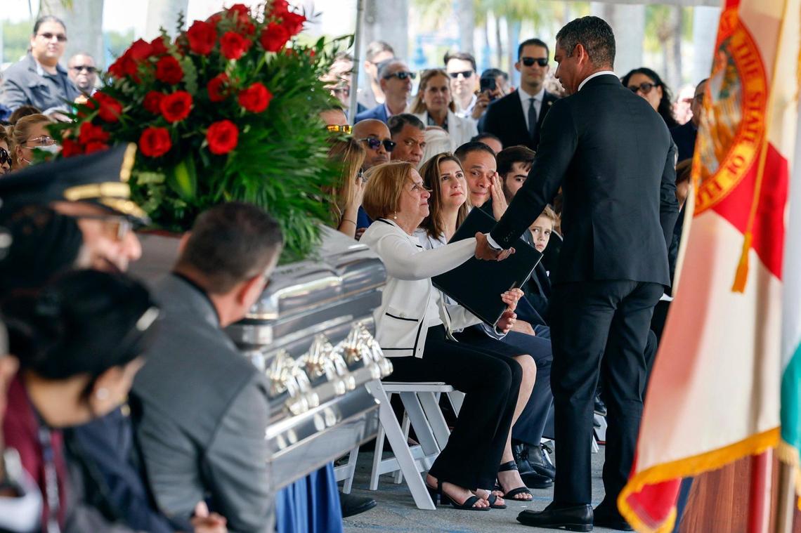 Chacha Reyes, the wife of Miami City Commissioner Manolo Reyes, who died on Thursday, receives a city proclamation for the commissioner from Miami Mayor Francis Suarez during a memorial service at Miami City Hall on Wednesday, April 16, 2025.